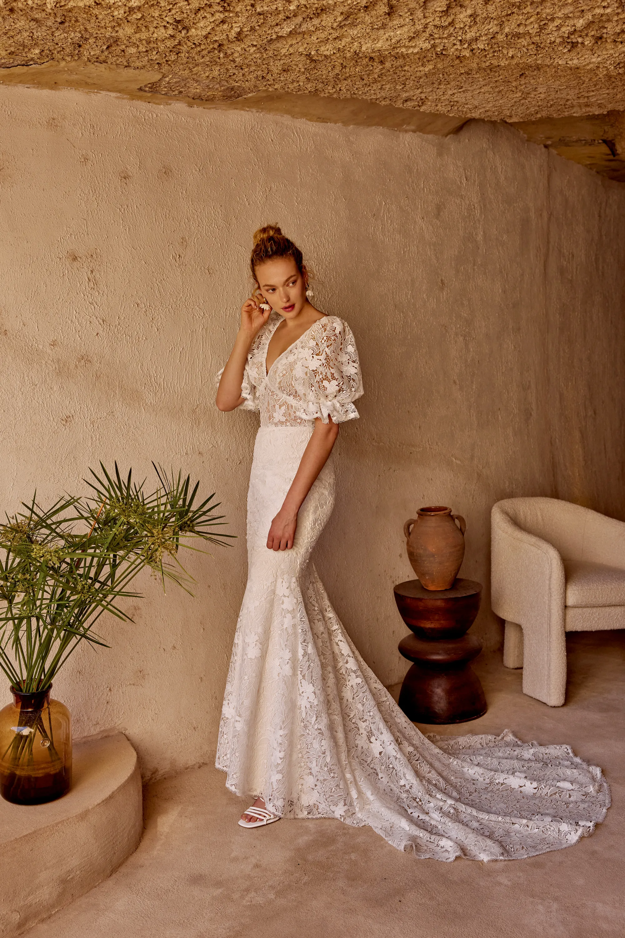 Braut in Spitzenkleid mit Puffärmeln unter einer natürlichen Felsdecke